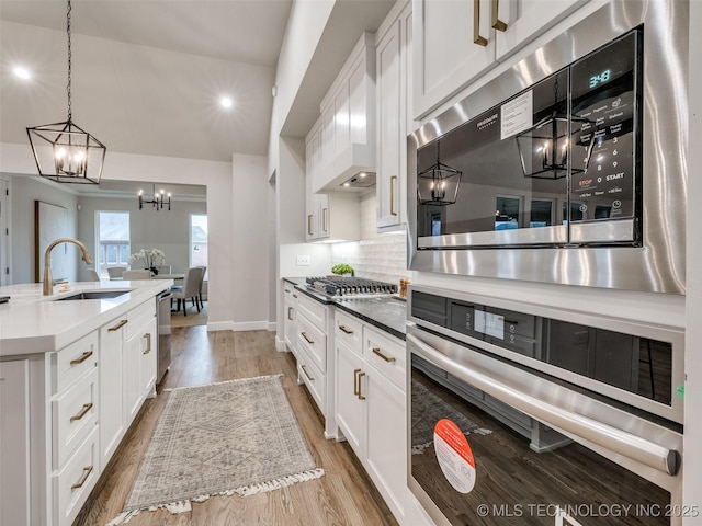 kitchen with hanging light fixtures, white cabinetry, and sink