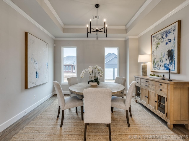 dining space with a tray ceiling, hardwood / wood-style floors, and a notable chandelier