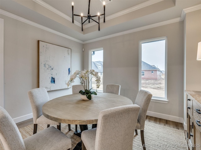 dining room featuring crown molding, a tray ceiling, light hardwood / wood-style floors, and a chandelier