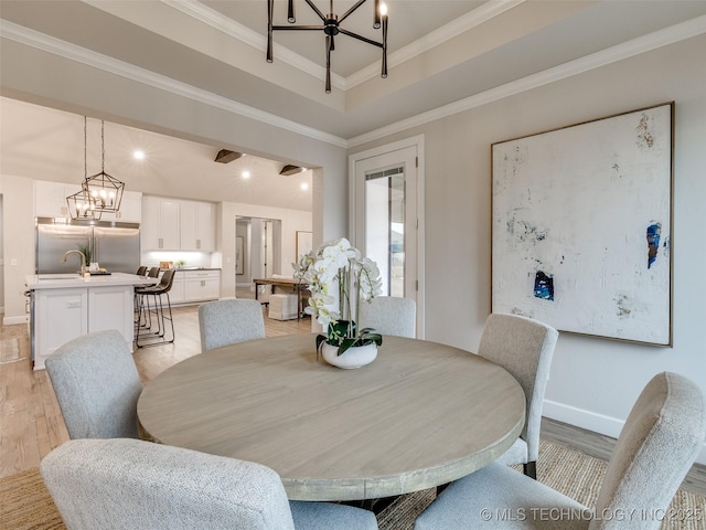 dining room with a notable chandelier, ornamental molding, and light hardwood / wood-style floors