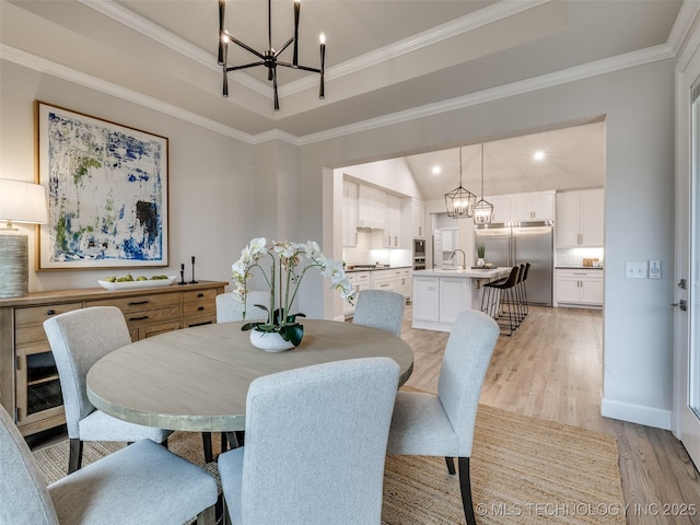 dining room with a raised ceiling, crown molding, and a notable chandelier