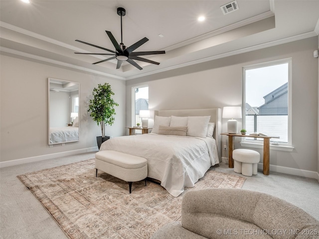 bedroom with multiple windows, a raised ceiling, and light carpet