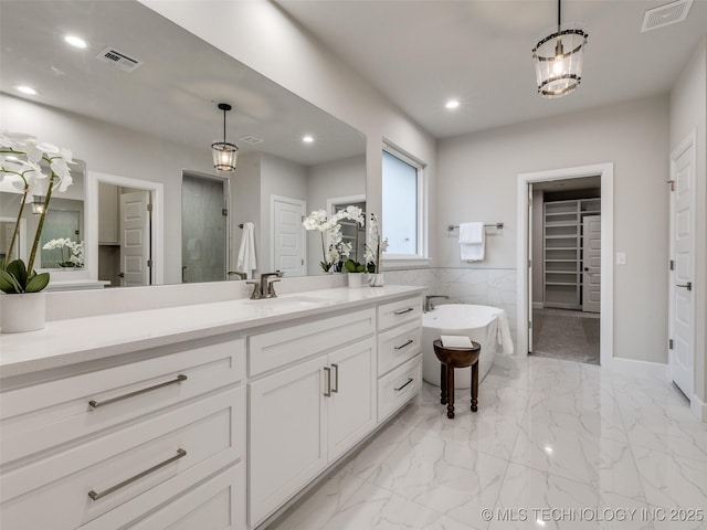 bathroom featuring vanity, independent shower and bath, and tile walls