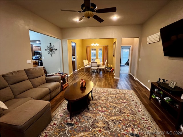 living room featuring ceiling fan with notable chandelier and dark hardwood / wood-style flooring