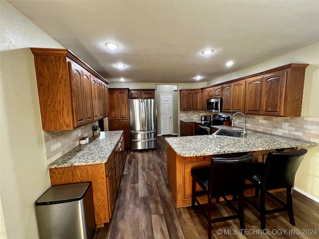 kitchen featuring sink, dark hardwood / wood-style flooring, backsplash, kitchen peninsula, and appliances with stainless steel finishes