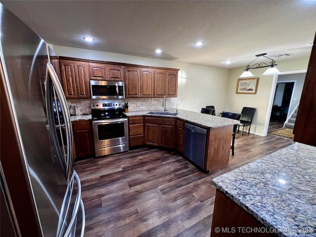 kitchen featuring backsplash, sink, decorative light fixtures, dark hardwood / wood-style flooring, and stainless steel appliances