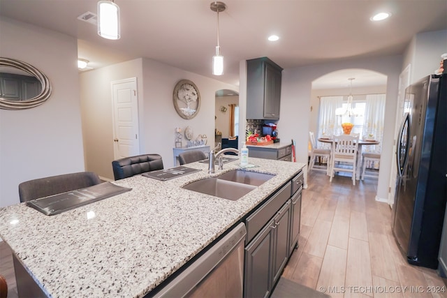 kitchen featuring appliances with stainless steel finishes, sink, hanging light fixtures, and an island with sink