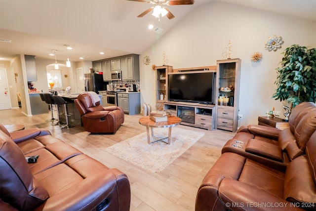 living room with light hardwood / wood-style floors, vaulted ceiling, and ceiling fan