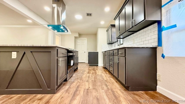 kitchen with tasteful backsplash, light stone counters, light hardwood / wood-style flooring, and crown molding