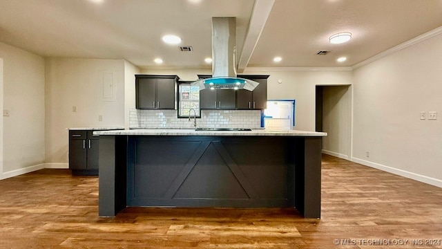 kitchen featuring light stone countertops, a center island, ornamental molding, and light hardwood / wood-style flooring