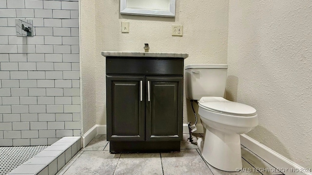 bathroom featuring toilet, vanity, and tiled shower