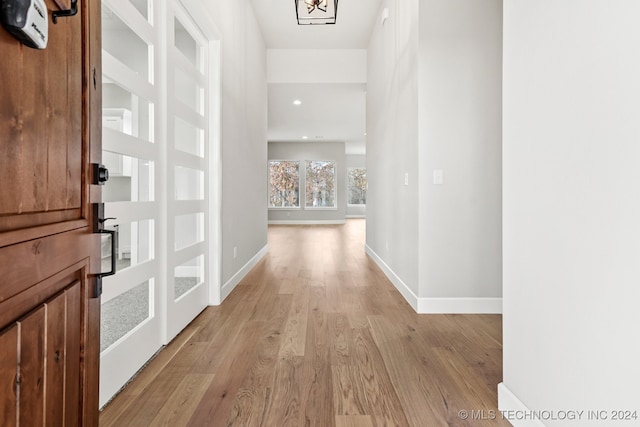 hall with light hardwood / wood-style floors and an inviting chandelier