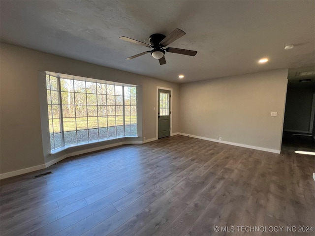 empty room with dark wood-style floors, recessed lighting, visible vents, and baseboards