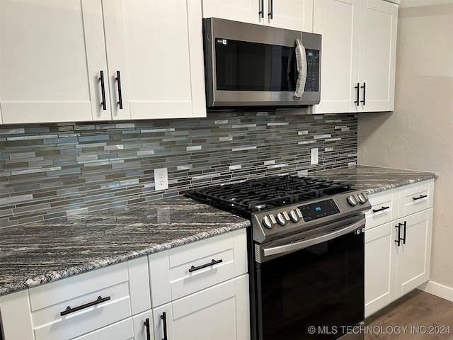 kitchen featuring appliances with stainless steel finishes, dark stone countertops, decorative backsplash, and white cabinets