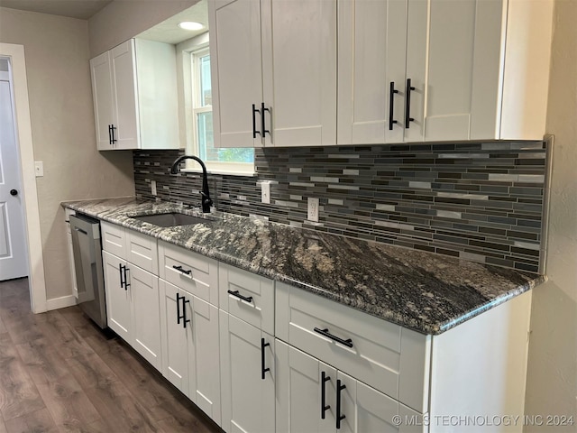 kitchen featuring decorative backsplash, dark stone counters, a sink, white cabinetry, and stainless steel dishwasher