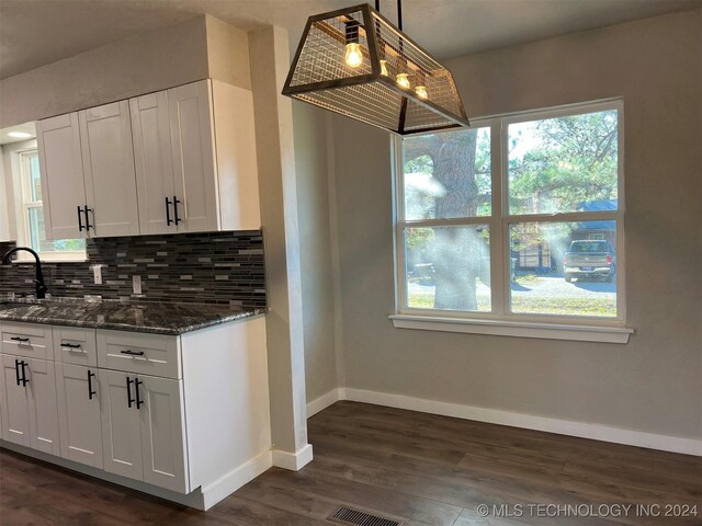 kitchen featuring tasteful backsplash, white cabinetry, pendant lighting, and dark stone counters