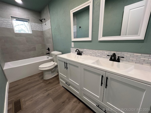 full bathroom with visible vents, decorative backsplash, a sink, and wood finished floors