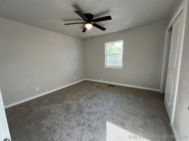 unfurnished bedroom with dark colored carpet, visible vents, ceiling fan, and baseboards