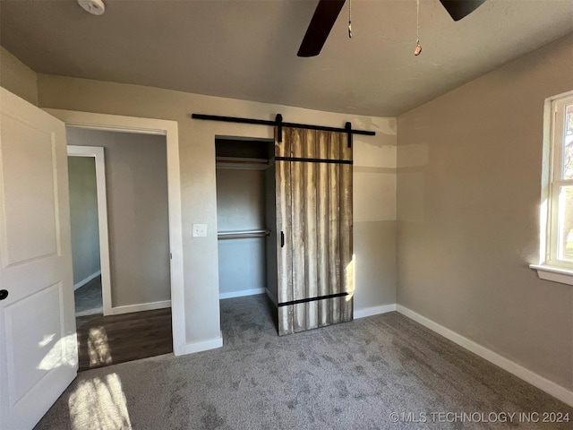 unfurnished bedroom featuring carpet floors, a barn door, and baseboards