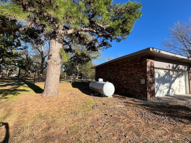 view of property exterior with brick siding, a detached garage, and fence