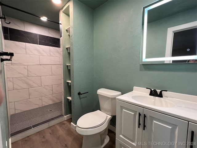 full bathroom with a textured wall, toilet, a stall shower, vanity, and wood finished floors