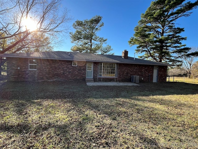 rear view of property featuring brick siding, a lawn, and a chimney