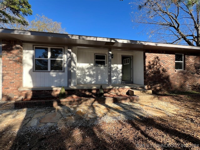 view of exterior entry with covered porch and brick siding