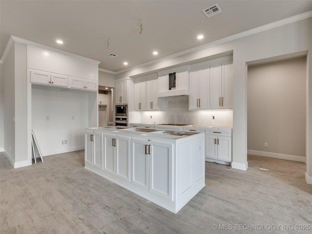 kitchen featuring light hardwood / wood-style floors, a center island with sink, crown molding, appliances with stainless steel finishes, and white cabinets