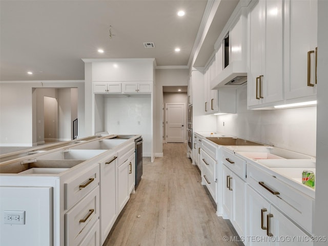 kitchen featuring white cabinetry, wall chimney range hood, black electric stovetop, light wood-type flooring, and crown molding