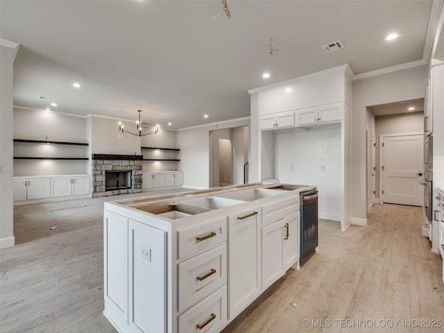 kitchen featuring dishwasher, a fireplace, a kitchen island, white cabinetry, and stainless steel oven