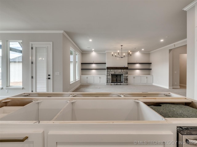 kitchen with ornamental molding, a chandelier, a stone fireplace, and decorative light fixtures