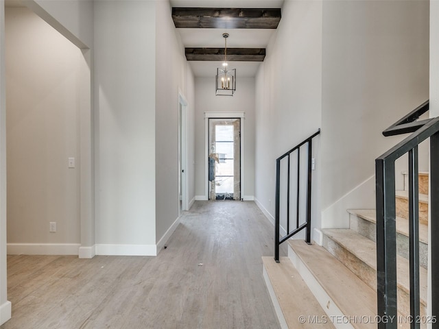 entrance foyer with a notable chandelier, beamed ceiling, and light wood-type flooring