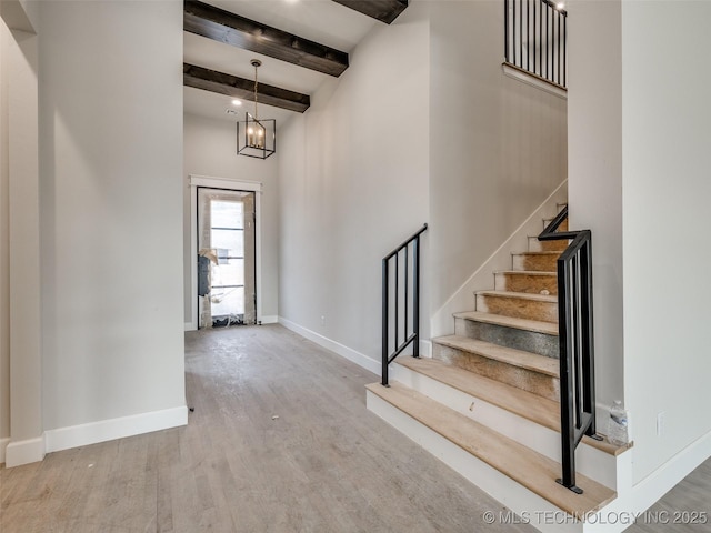 foyer featuring a high ceiling, hardwood / wood-style floors, beam ceiling, and a notable chandelier