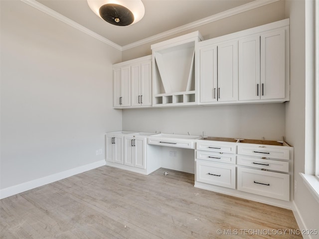 unfurnished office featuring light hardwood / wood-style flooring, crown molding, and built in desk