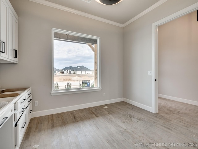 unfurnished dining area with light hardwood / wood-style floors and ornamental molding