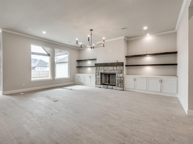 unfurnished living room with light hardwood / wood-style floors, a fireplace, ornamental molding, and a notable chandelier