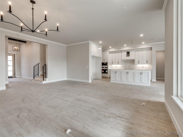 unfurnished living room with light wood-type flooring, a notable chandelier, and crown molding