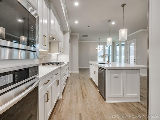 kitchen with visible vents, appliances with stainless steel finishes, ornamental molding, and a sink