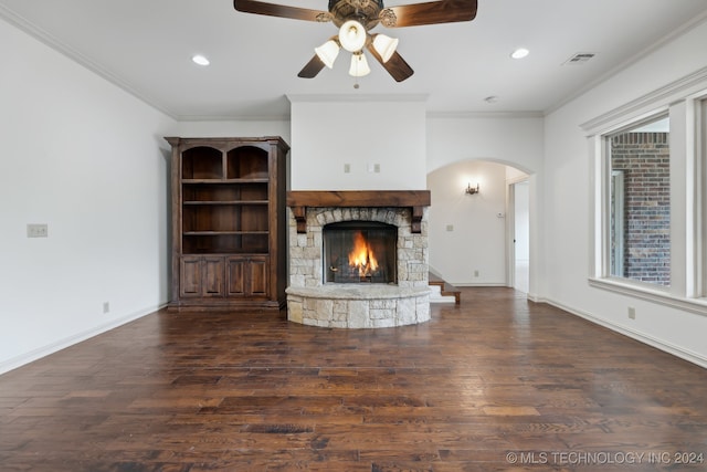 unfurnished living room featuring dark hardwood / wood-style flooring, a stone fireplace, a wealth of natural light, and ornamental molding