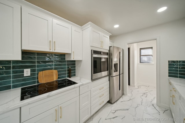 kitchen with light stone countertops, white cabinetry, backsplash, and appliances with stainless steel finishes