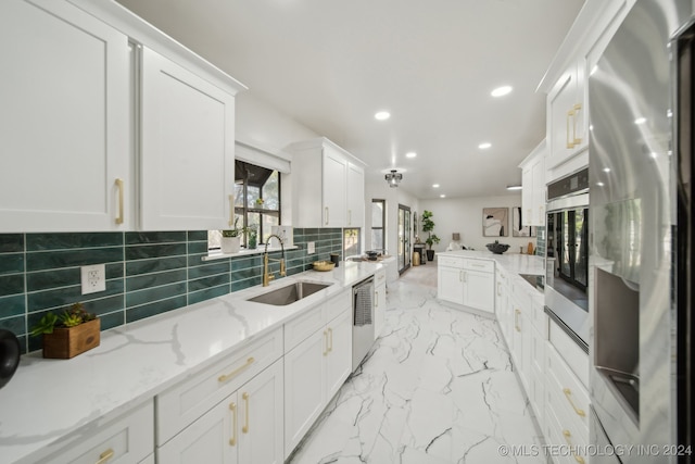 kitchen with white cabinetry, sink, light stone countertops, tasteful backsplash, and appliances with stainless steel finishes