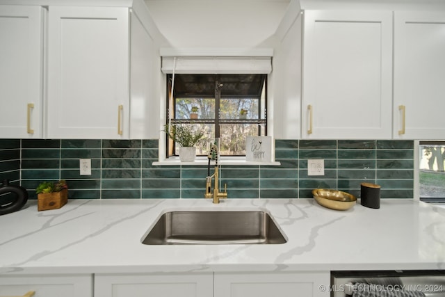 kitchen featuring white cabinets, sink, stainless steel dishwasher, light stone countertops, and tasteful backsplash