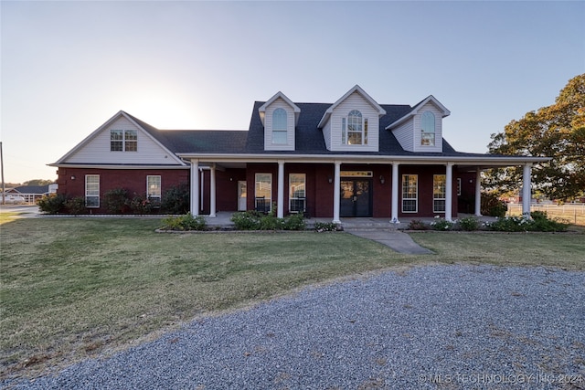 cape cod house with a porch and a lawn