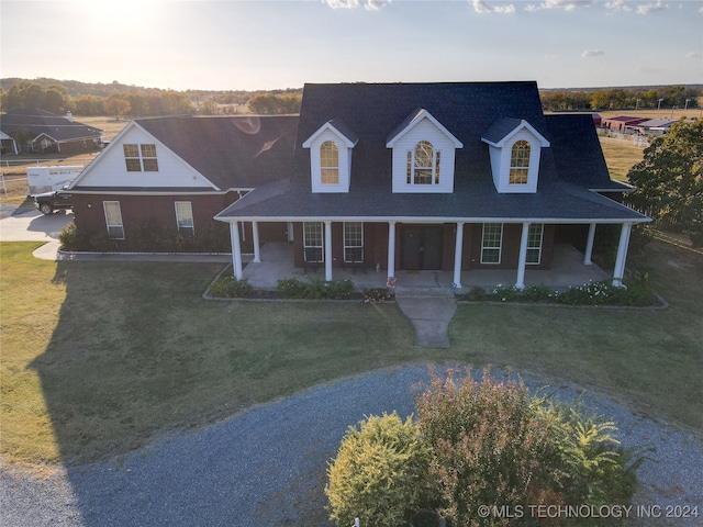 new england style home featuring covered porch and a front lawn