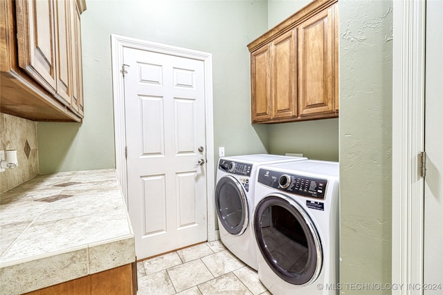 laundry area with cabinets, washer and clothes dryer, and light tile patterned flooring