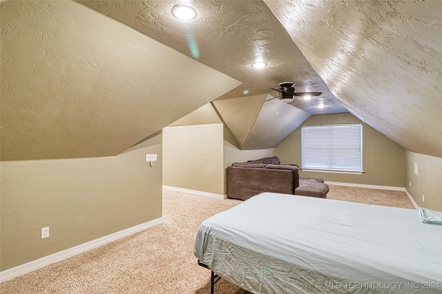 carpeted bedroom with a textured ceiling, vaulted ceiling, and ceiling fan