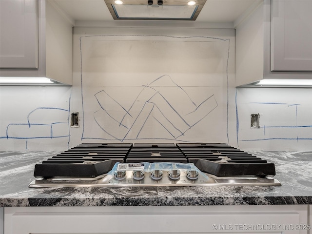 room details with dark stone countertops, white cabinetry, and gas stovetop