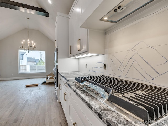 kitchen with appliances with stainless steel finishes, wall chimney exhaust hood, white cabinetry, vaulted ceiling, and light stone counters