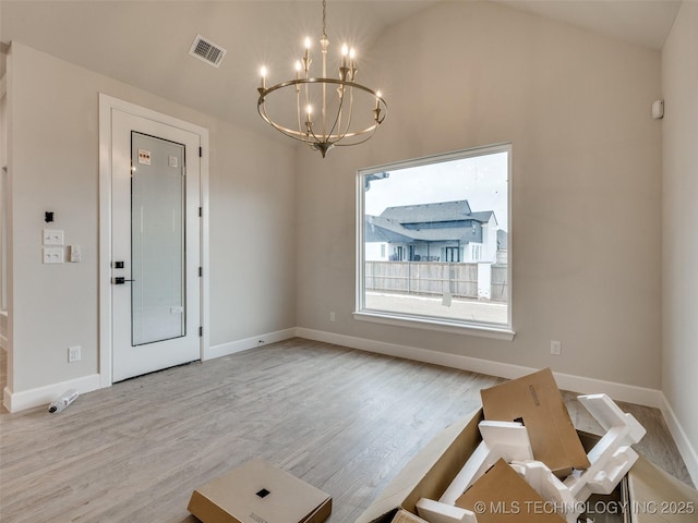 unfurnished dining area with light wood-type flooring, vaulted ceiling, and an inviting chandelier