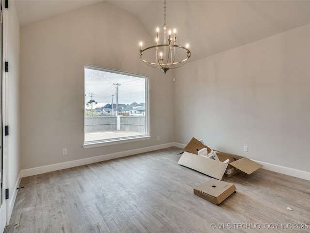 unfurnished dining area featuring lofted ceiling, a notable chandelier, and light hardwood / wood-style flooring